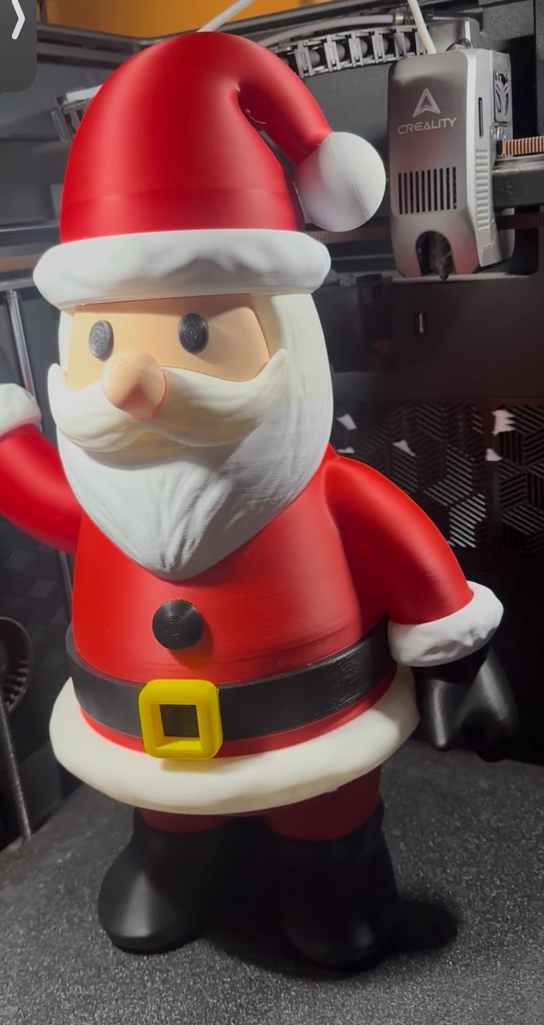 May include: A 3D-printed Santa Claus figure. The figure is wearing a red suit with a black belt and a yellow buckle. The hat is red with a white trim and a white pom-pom. The face is tan with a white beard and mustache.