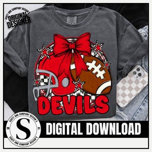 Puede incluir: Camiseta de manga larga gris oscuro con un casco y un balón de fútbol americano rojos, un lazo rojo y detalles de estrellas. La palabra "DEVILS" es roja. El texto "DIGITAL DOWNLOAD" está debajo.