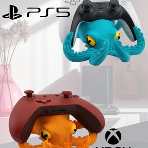 May include: A teal octopus-shaped controller stand holding a white and black PS5 controller, and an orange octopus-shaped controller stand holding a dark red Xbox controller. The PS5 and Xbox logos are visible near their respective controllers.