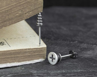 May include: Two silver screw-shaped earrings. One earring features a screw head with a plus sign, the other earring features a screw head with a spiral design.