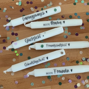 Könnte beinhalten: Fünf weiße Kerzen mit verschiedenen Botschaften darauf geschrieben. Die Botschaften lauten "Lieblingsmensch", "Beste Mama", "Glückslicht", "Freundschaftslicht", "Geburtstagslicht" und "Beste Freundin".