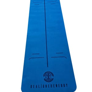 May include: A blue yoga mat with a central vertical line and horizontal alignment markers. The mat has the text "REALIGNEDENERGY" below a tree-of-life logo. The mat is designed for yoga and fitness.