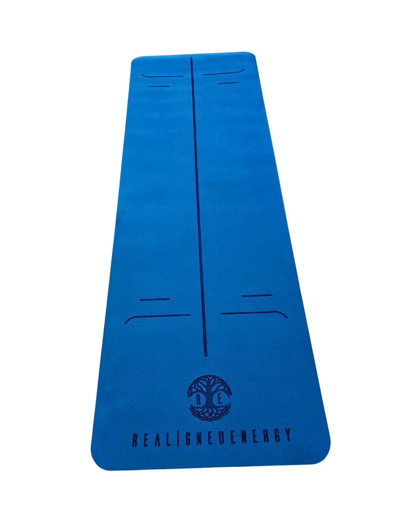 May include: A blue yoga mat with a central vertical line and horizontal alignment markers. The mat has the text "REALIGNEDENERGY" below a tree-of-life logo. The mat is designed for yoga and fitness.