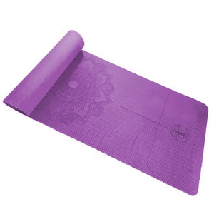 May include: A rolled-up purple yoga mat with a textured surface and a mandala design. The mat is partially unrolled, revealing a detailed floral pattern and alignment lines. The yoga mat is designed for exercise and meditation.
