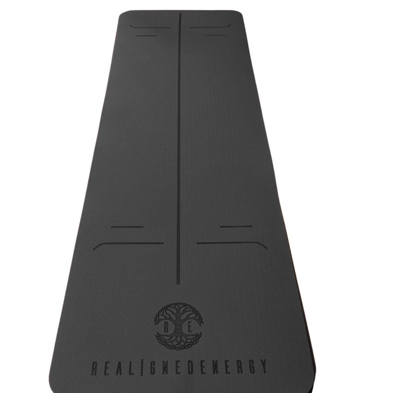 May include: Black yoga mat with alignment lines and the text "REALIGNEDENERGY". The mat features a tree of life logo. The mat is designed for yoga and fitness activities.