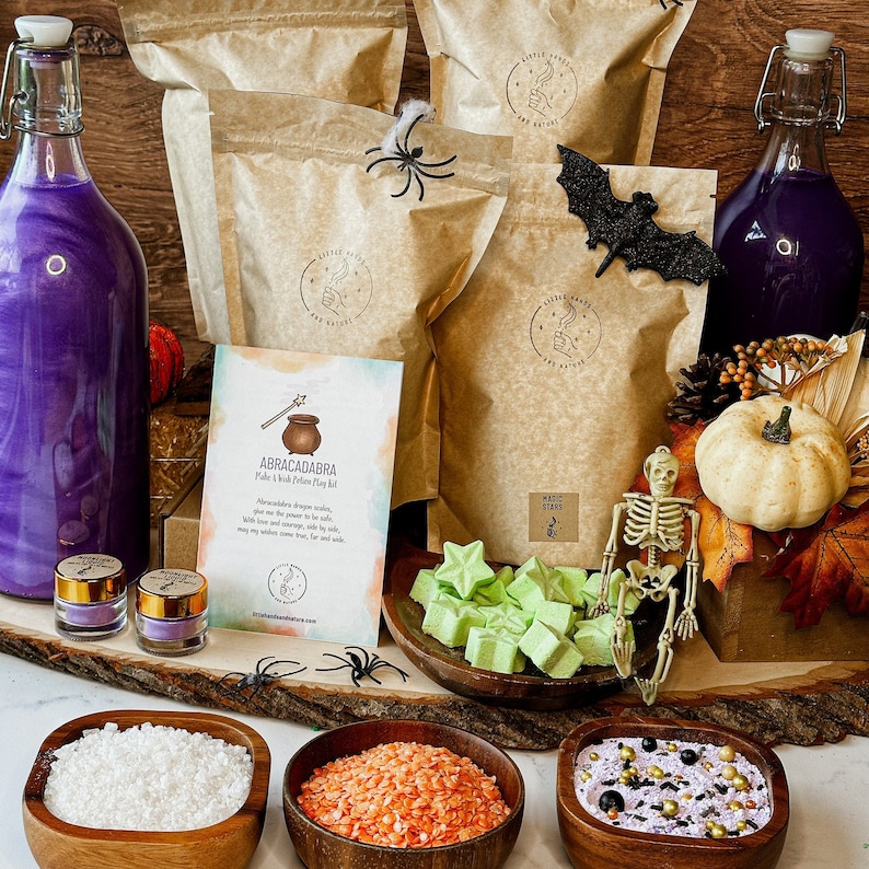 May include: A Halloween-themed craft kit with a purple potion bottle, brown paper bags, a skeleton figurine, and a card that reads "ABRACADABRA Make a Witch Potion Play Doh Kit".