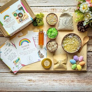 Puede incluir: Un kit de alegr&iacute;a arco&iacute;ris para ni&ntilde;os con ingredientes naturales. El kit incluye un taz&oacute;n de madera, una peque&ntilde;a bolsa de brillantina colorida, un peque&ntilde;o frasco de miel, un peque&ntilde;o taz&oacute;n de musgo verde, un peque&ntilde;o taz&oacute;n de papel triturado, un peque&ntilde;o taz&oacute;n de burbujas de jab&oacute;n, una cuchara de madera y una peque&ntilde;a bolsa de huevos coloridos. El kit tambi&eacute;n incluye dos tarjetas con el texto "Estoy permitido ser ruidoso" y "Kit de alegr&iacute;a arco&iacute;ris".