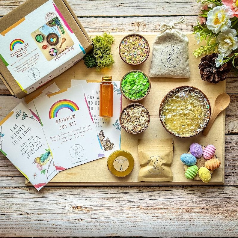 Puede incluir: Un kit de alegr&iacute;a arco&iacute;ris para ni&ntilde;os con ingredientes naturales. El kit incluye un taz&oacute;n de madera, una peque&ntilde;a bolsa de brillantina colorida, un peque&ntilde;o frasco de miel, un peque&ntilde;o taz&oacute;n de musgo verde, un peque&ntilde;o taz&oacute;n de papel triturado, un peque&ntilde;o taz&oacute;n de burbujas de jab&oacute;n, una cuchara de madera y una peque&ntilde;a bolsa de huevos coloridos. El kit tambi&eacute;n incluye dos tarjetas con el texto "Estoy permitido ser ruidoso" y "Kit de alegr&iacute;a arco&iacute;ris".