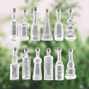 May include: A collection of 16 clear glass bottles with various shapes and sizes. The bottles have a variety of textures and designs, including smooth, ribbed, and embossed.