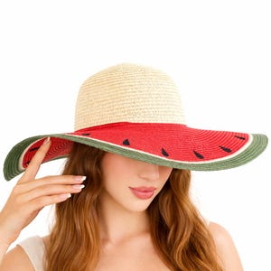 May include: A straw sun hat with a wide brim, featuring a watermelon design. The hat has a natural straw crown, a red band with black seed accents, and a green edge. The brim is wide, offering sun protection.