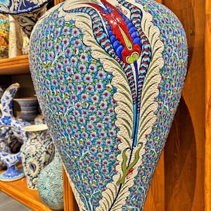 May include: A large, blue and white ceramic vase with a floral design. The vase features a large, red and blue tulip with green leaves. The vase is decorated with a pattern of small, white flowers.