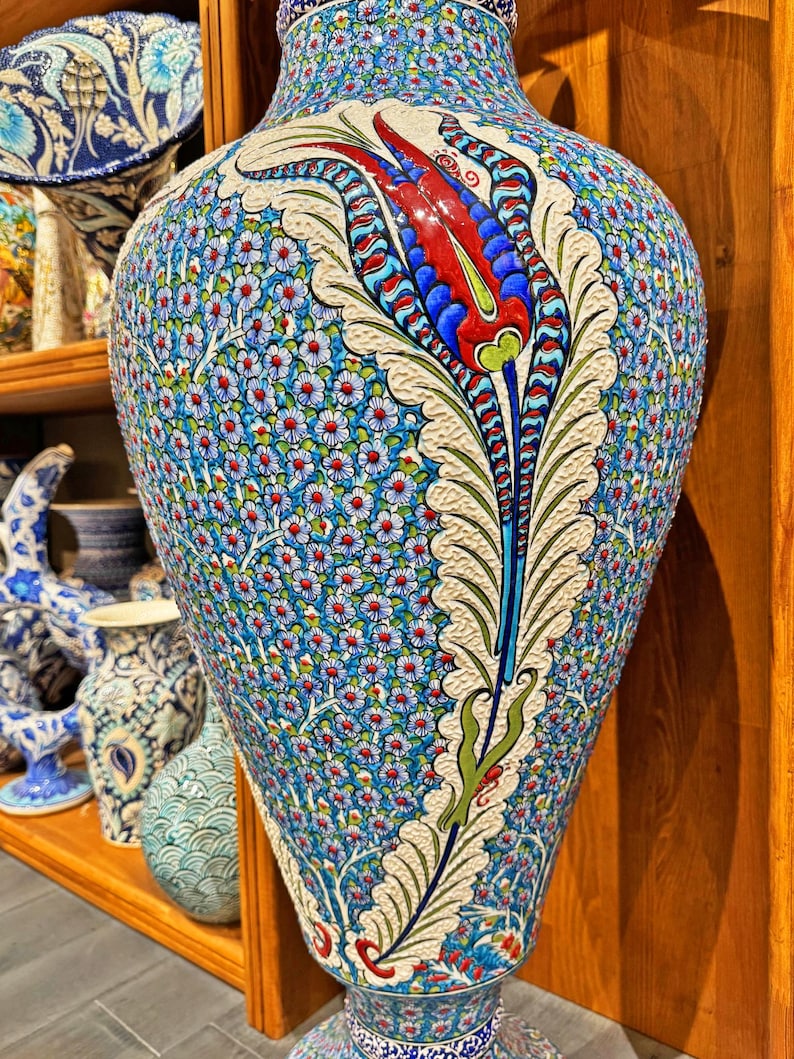 May include: A large, blue and white ceramic vase with a floral design. The vase features a large, red and blue tulip with green leaves. The vase is decorated with a pattern of small, white flowers.