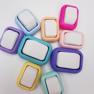 May include: A collection of nine rectangular objects, each featuring a white center piece surrounded by a colored frame. The frames are in various shades including light blue, purple, teal, yellow, peach, pink, and dark purple, arranged in a cluster.
