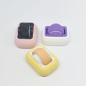 May include: Three small, colourful, 3D printed rollers with different coloured wheels. The rollers are designed to be used with a fidget toy or other small object.