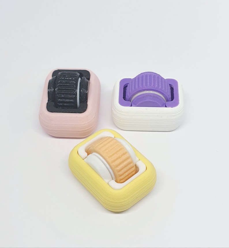 May include: Three small, colourful, 3D printed rollers with different coloured wheels. The rollers are designed to be used with a fidget toy or other small object.