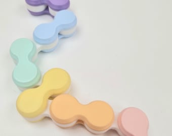 May include: A flexible, articulated fidget toy composed of six connected, peanut-shaped segments in a gradient of pastel colors including purple, blue, mint green, yellow, orange, and pink, each featuring a white base and rounded edges.