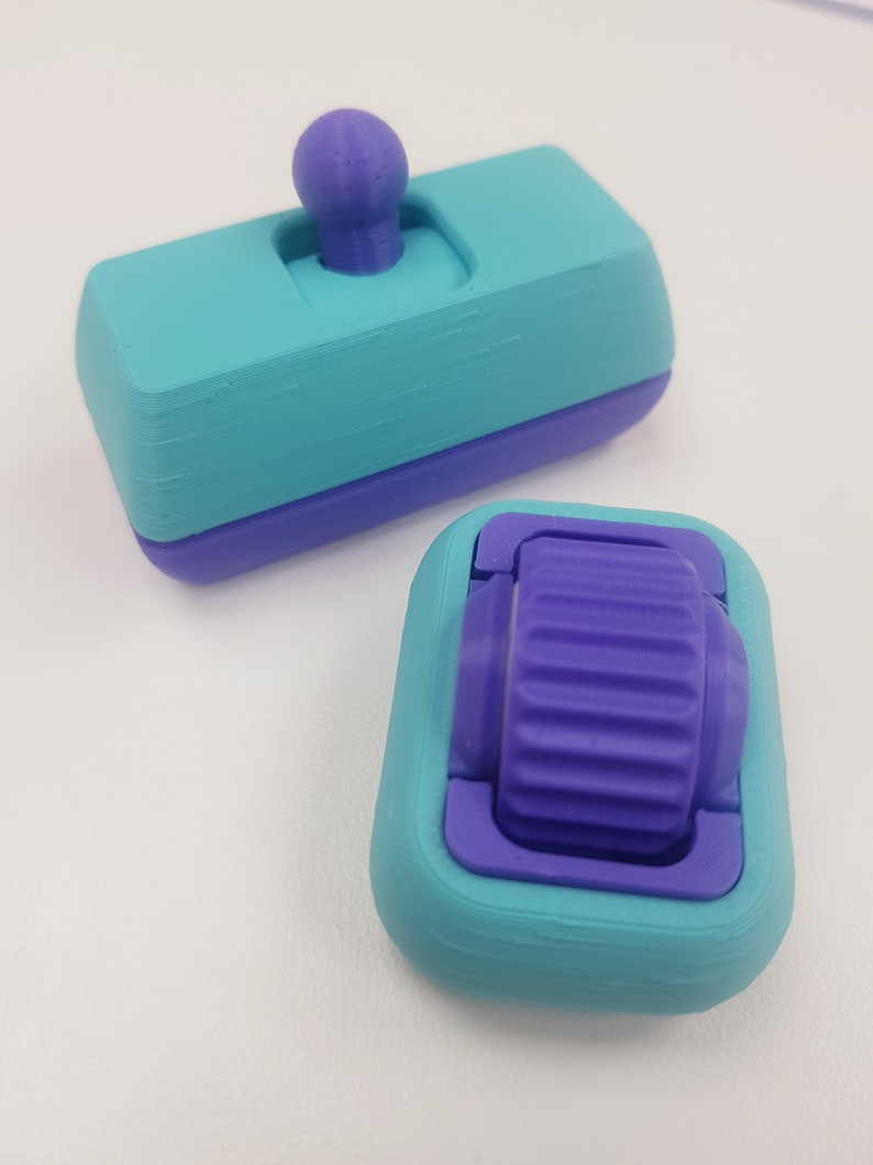 May include: Two 3D printed objects, one is a teal and purple toggle switch with a purple knob, the other is a teal and purple wheel with a purple gear.