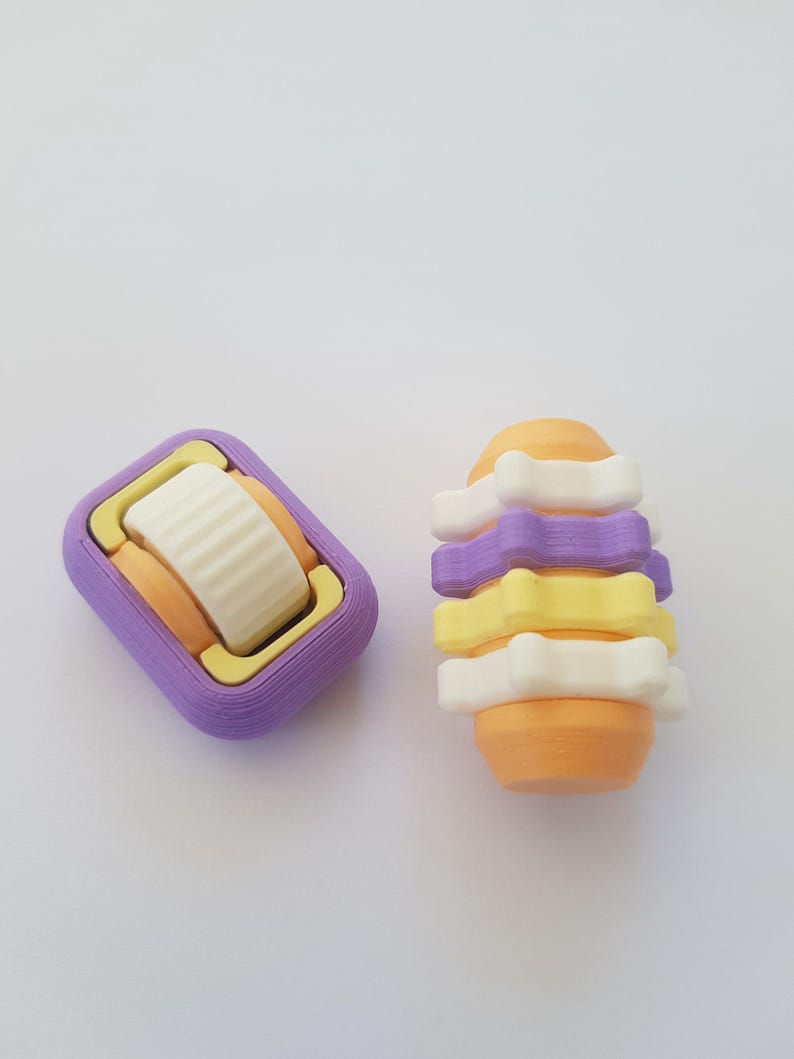 May include: Two 3D printed toys, one is a purple and orange rectangle with a white wheel, the other is a stack of orange, yellow, and white rings.