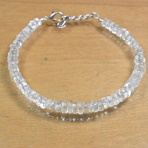 May include: A clear quartz bracelet with a silver-colored clasp. The bracelet is made of small, faceted, clear quartz beads strung together. The beads are uniform in size and shape, creating a delicate and elegant piece of jewelry.