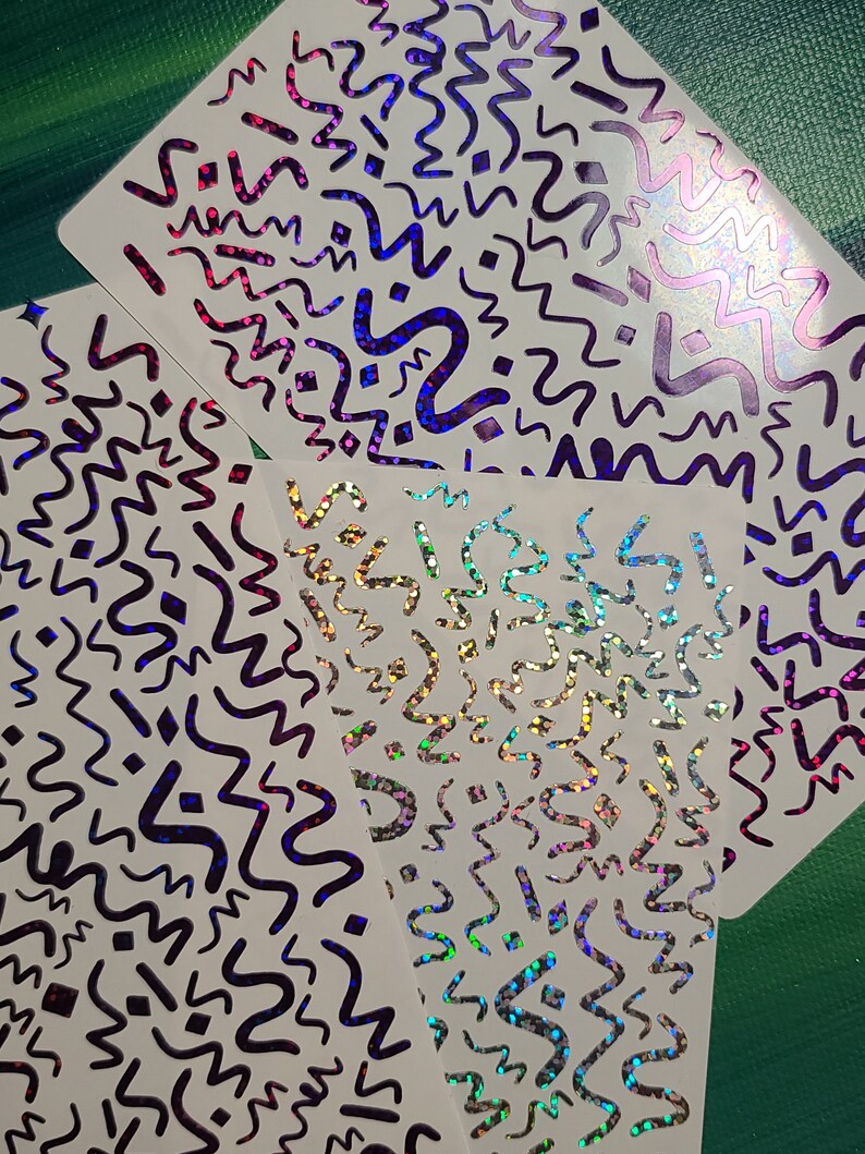 May include: Four sheets of white paper with a holographic, iridescent finish. Each sheet has a repeating pattern of black wavy lines and shapes.
