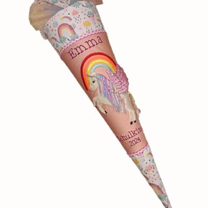 May include: A pink and white school cone with a unicorn and rainbow design. The cone is decorated with a pink tulle bow and has the name "Emma" and the year "2024" written on it.
