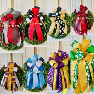 May include: A collection of 10 wreaths with different colored bows. The bows are made of ribbon and are tied in a variety of styles. The wreaths are all green and are made of artificial greenery.