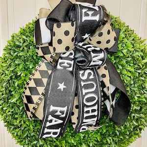 May include: A green boxwood wreath with a black and white ribbon bow. The ribbon has the words "Farmhouse" and "Farm Fresh" printed on it.