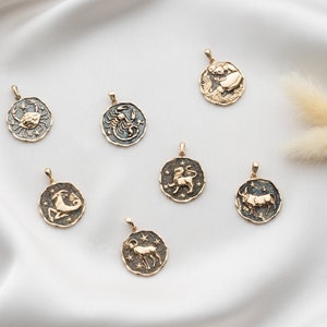 Puede incluir: Un conjunto de siete colgantes de oro del zod&iacute;aco con fondo de esmalte negro. Cada colgante presenta un signo del zod&iacute;aco diferente: C&aacute;ncer, Escorpio, Leo, Capricornio, Tauro, Acuario y Aries.
