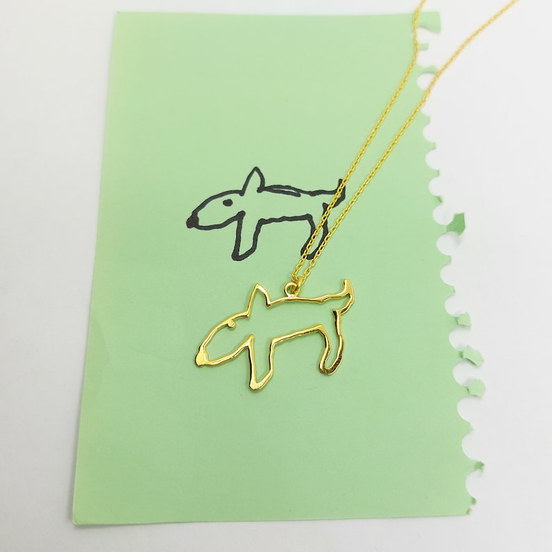 Personalized necklace from a drawing of a dog laid on a mint piece of paper