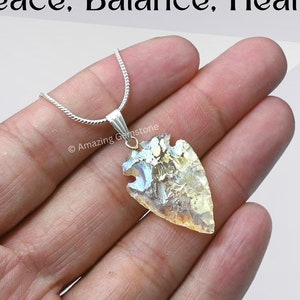 May include: A silver chain necklace with a clear, iridescent arrowhead pendant. The pendant is made of natural crystal and is a beautiful example of the healing power of crystals.