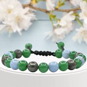 May include: A bracelet made of green, blue, and gray beads. The bracelet is made of natural stones and has a black cord.