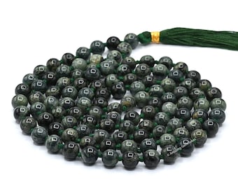 May include: A green and black stone mala necklace with a green tassel. The beads are round and have a speckled pattern.