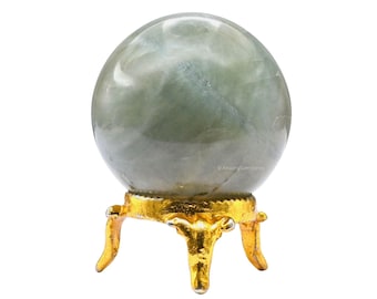 Puede incluir: Una bola de cristal verde sobre un soporte dorado con tres patas.