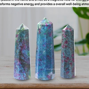 May include: Three green and pink crystal points, also known as ruby zoisite, are arranged in a row on a wooden surface. The crystals are different sizes and have a natural, rough texture.
