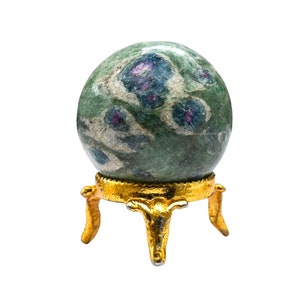 Könnte beinhalten: Eine grüne und blaue Edelsteinkugel mit rosa Einschlüssen, die auf einem goldenen Metallständer mit drei Beinen präsentiert wird.