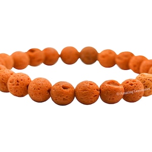 May include: A bracelet made of orange lava rock beads. The beads are round and have a rough, textured surface.