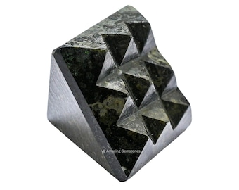 May include: A black and green pyramid-shaped crystal with a textured surface. The crystal is carved with a pattern of small triangles.