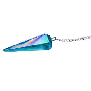 Op de afbeelding: Een blauwe, iriserende kristallen slinger met een zilveren ketting. De kristal is puntig en heeft een regenboogkleurige glans.