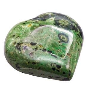 Puede incluir: Una piedra preciosa en forma de coraz&oacute;n con una superficie pulida. La piedra presenta una mezcla de tonos verdes con inclusiones negras y moradas. La gema tiene una forma suave y redondeada y un acabado brillante. La imagen est&aacute; sobre un fondo blanco.