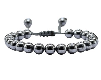 May include: A silver beaded bracelet with a sliding knot closure. The bracelet is made of round, smooth beads.