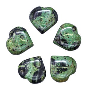 Puede incluir: Cinco piedras en forma de coraz&oacute;n con patrones verdes y negros. Las piedras pulidas muestran diferentes tonos de verde, con vetas negras oscuras. La disposici&oacute;n est&aacute; centrada en un fondo blanco. Las piedras miden unos 3-4 cm de largo.