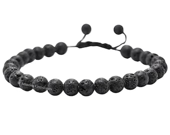 Puede incluir: Pulsera de cuentas de piedra de lava negra. La pulsera presenta cuentas redondas y porosas ensartadas con un cordón negro ajustable. Las cuentas son de color gris oscuro y tienen una superficie texturizada. El texto "Amazing Gemstones" es visible en una de las cuentas.