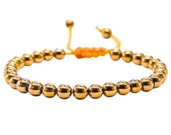 May include: Gold-colored beaded bracelet with adjustable orange and yellow cord. The bracelet features multiple small, round beads. The cord is knotted and has small gold-colored beads at the ends.