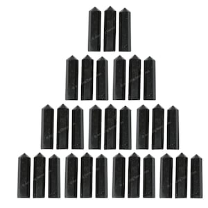 May include: A triangular arrangement of 21 black obsidian crystal points. The points are arranged in a pyramid shape, with the largest point at the top and the smallest points at the bottom.