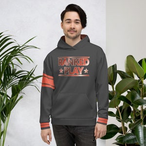 Op de afbeelding: Een donkergrijze hoodie met de tekst "RANKED PLAY" in een rood en wit gradiënt ontwerp. De hoodie heeft een rode streep op de linkermouw en rode biezen op de manchetten en capuchon.