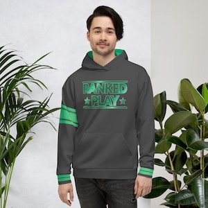 May include: A dark gray hoodie with the text "RANKED PLAY" in green. The hoodie has green accents on the hood, sleeves, and cuffs. The design includes stars and stripes.