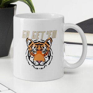 May include: White ceramic mug with a tiger face and the text "GO GET 'EM" in gold lettering.