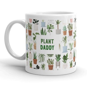 May include: White ceramic mug with a green and brown illustration of potted plants and the text "PLANT DADDY" in green.