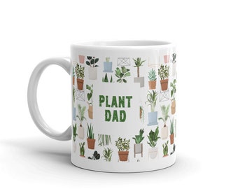 Peut inclure: Une tasse en céramique blanche avec un motif vert et blanc de plantes en pot. Le texte "PLANT DAD" est imprimé en vert sur la tasse.