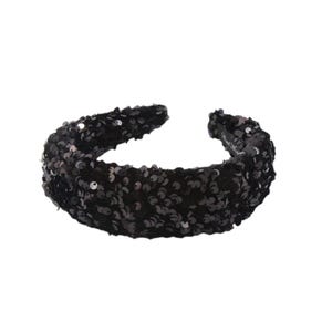 Pode incluir: Uma tiara preta com lantejoulas. A tiara é coberta por pequenas e brilhantes lantejoulas pretas. O acessório é uma faixa larga, projetada para ser usada na testa. A tiara é um acessório de moda.